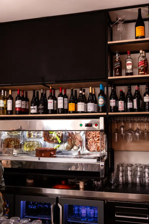Barra de Taberna Quimera con botellero, vinos y vitrina