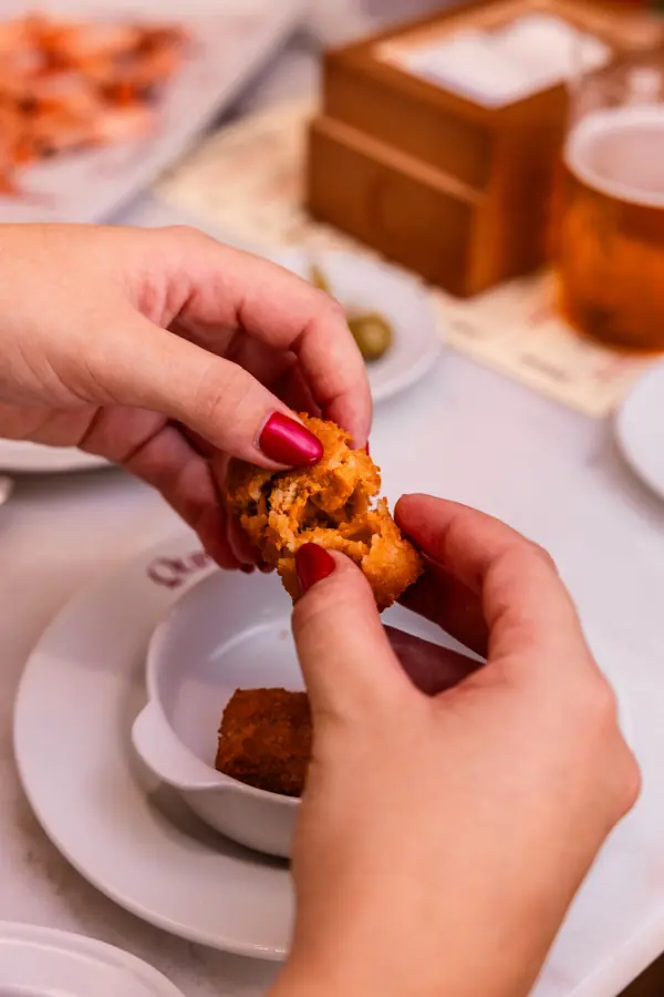 Manos abriendo una croqueta recién hecha