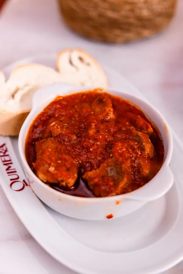 Guiso con tomate en cazuelita, con pan, en Taberna Quimera