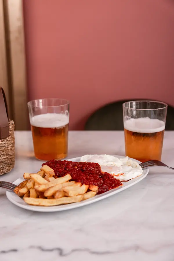 Patatas fritas con tomate y huevos fritos, con dos cañas